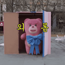 a pink teddy bear with a blue bow is in a box with chinese writing on it