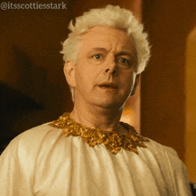 a man with white hair is wearing a white robe with gold trim