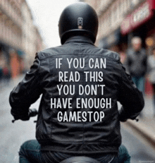 a man wearing a helmet and a leather jacket with the words if you can read this you don 't have enough gamestop