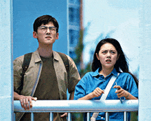 a man and a woman standing next to each other looking out of a window