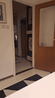 a door that is open to a hallway with pictures on the wall and a rug on the floor