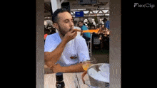 a man is sitting at a table eating a sandwich and drinking a beer .