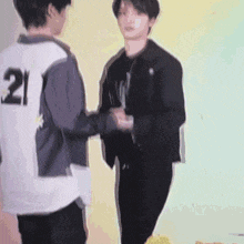 two young men are shaking hands and one has the number 21 on his back .