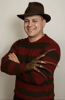 a man wearing a hat and a sweater with a claws glove