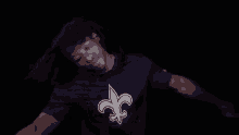 a man wearing a purple t-shirt with a saints logo on it is dancing .