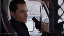 a man is looking through binoculars while sitting in the driver 's seat of a vehicle .