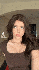 a woman with long brown hair is taking a selfie with a tiktok app on her phone
