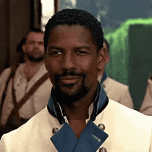 a man with a beard is wearing a white jacket and smiling .
