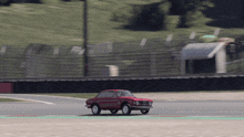 a red car is driving on a track with a green stripe on the side