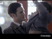 a man in a suit and tie is holding a small child