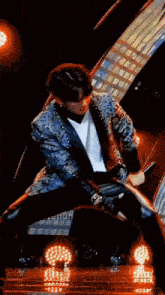 a man in a blue jacket is holding a microphone in his hand