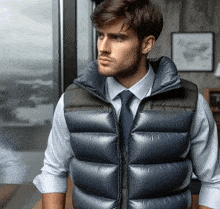 a man wearing a vest and tie is looking out a window