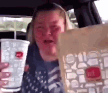 a woman is sitting in a car holding a bag of mcdonald 's fries .