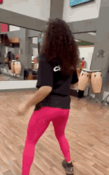 a woman in pink leggings is dancing in a dance studio in front of a mirror .