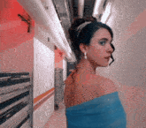 a woman in a blue dress is standing in a hallway and looking over her shoulder