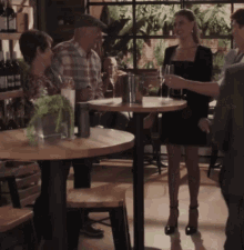 a woman in a black dress stands in a restaurant