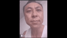 a man is making a funny face while wearing a white tank top .