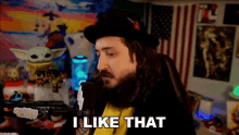 a man with long hair and a beard is talking into a microphone and saying i like that .