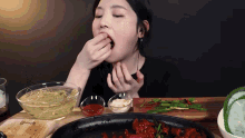a woman is sitting at a table eating food from a bowl