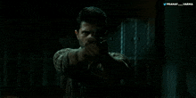 a man is holding a gun in a dark room with a twitter logo behind him