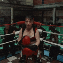 a woman is in a boxing ring with a man in the background