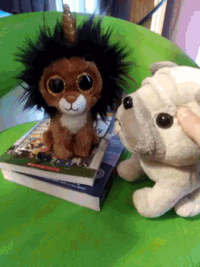 two stuffed animals are sitting on top of a stack of books one of which is titled " from the beginning "