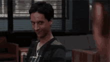a man is making a funny face while sitting in front of a window .
