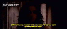 a woman is standing in front of a window with a quote that says `` when we were younger and we wanted to cry we were