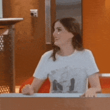 a woman wearing a t-shirt with the letter n on it is sitting at a table .