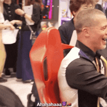 a man in a black shirt is laughing while holding a red chair with the words ahahaaa written on it
