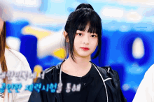a girl with a ponytail looks at the camera with a blue background behind her