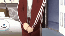 a person in a red jacket with white stripes is standing in a bedroom