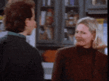 a man and a woman are standing next to each other in a kitchen and talking to each other .
