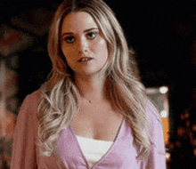 a woman is wearing a pink sweater and a white tank top .
