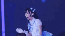 a girl with long black hair is wearing a blue and white dress and a microphone .