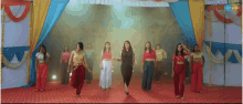 a group of women are dancing on a stage with a tv channel displayed on the bottom