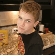 a young boy is standing in front of a box of rice balls