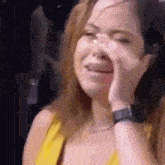 a woman in a yellow dress is crying while holding her hand to her face .