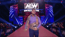 a man in a purple shirt is walking on a red carpet in front of a aew sign