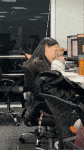 a woman sits at a desk in front of a computer with a bottle that says ' l' oreal '