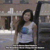 a woman in a tank top is standing next to a van with the words " you 're gonna need waders "