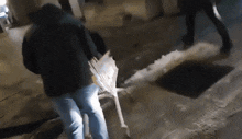 a man in a black jacket is pushing a wheelbarrow in the snow .