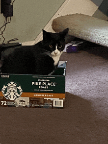 a black and white cat is sitting in a box of starbucks pike place roast
