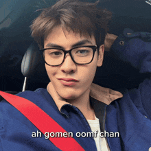 a young man wearing glasses and a blue jacket is sitting in a car with the words ah gomen oomf chan above him