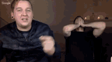 two men are dancing in front of a google logo in the corner