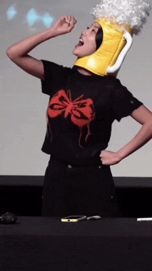 a woman wearing a yellow hat and a black shirt with a red butterfly on it