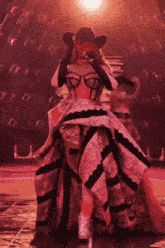 a woman is wearing a cowboy hat and a long dress while dancing on a stage .