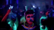 a woman with glow in the dark paint on her face is dancing in a crowd at a party