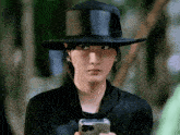 a woman wearing a black hat is holding a cellphone