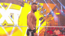 a wrestler is standing in a ring with the letter x in the back